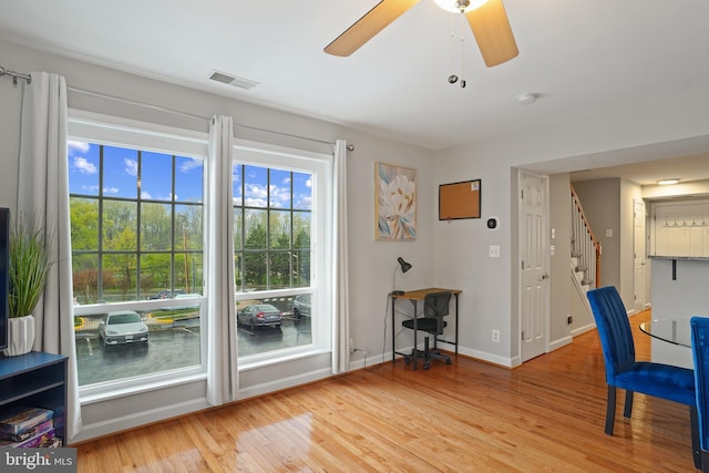 living area with baseboards, a ceiling fan, stairs, light wood-style floors, and visible vents