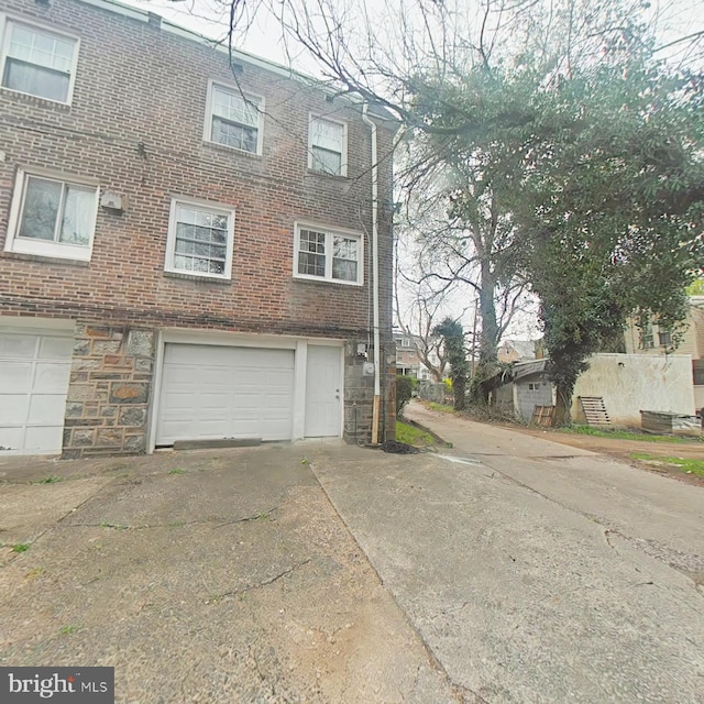 2710 N 47th St, Philadelphia, PA 19131 - view of side of property with driveway, an attached garage, brick siding, and stone siding