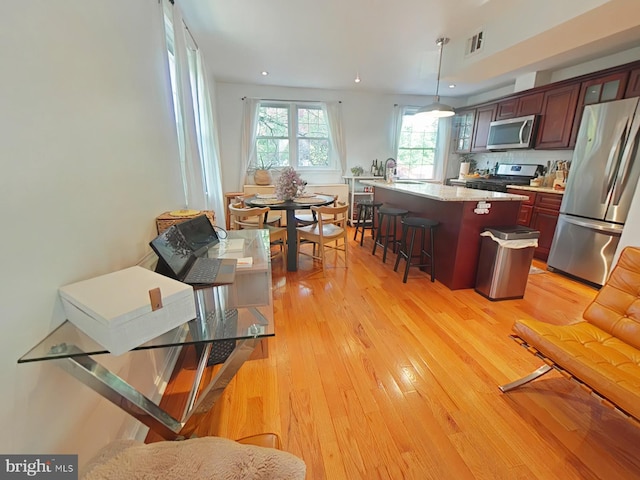 2710 N 47th St, Philadelphia, PA 19131 - kitchen with stainless steel appliances, a breakfast bar, light wood-type flooring, glass insert cabinets, and a center island with sink