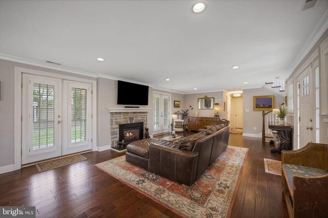 living area with baseboards, ornamental molding, a stone fireplace, dark wood-type flooring, and french doors