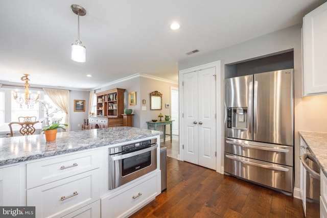 kitchen with dark wood-style flooring, light stone counters, white cabinets, appliances with stainless steel finishes, and hanging light fixtures