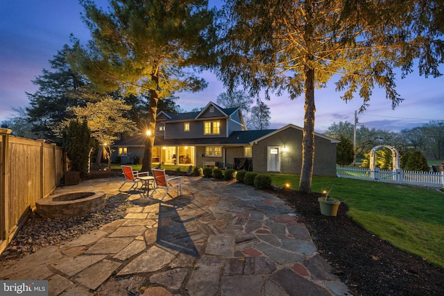 rear view of property with a patio area, a fire pit, a fenced backyard, and a lawn