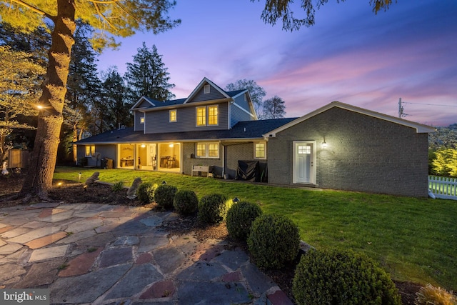 view of front of home featuring a yard, fence, and brick siding