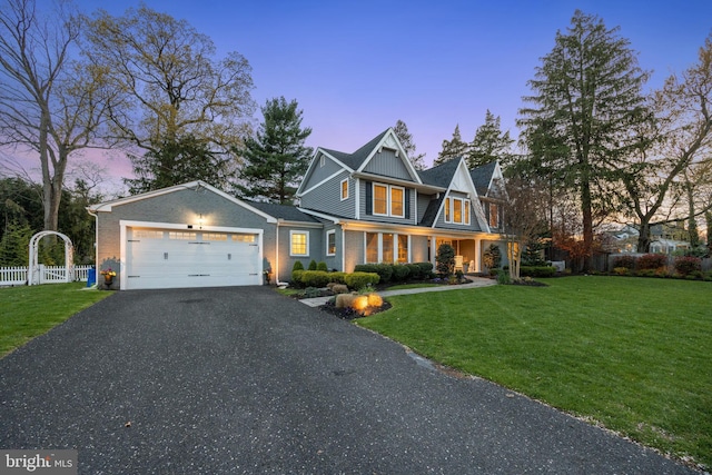 view of front of home featuring aphalt driveway, a front yard, fence, brick siding, and an attached garage