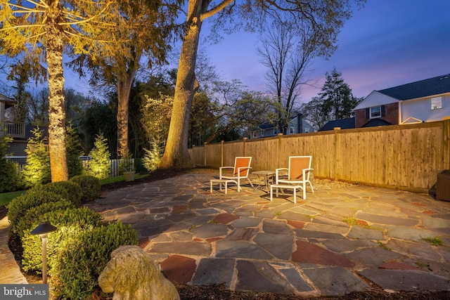 patio terrace at dusk featuring a fenced backyard