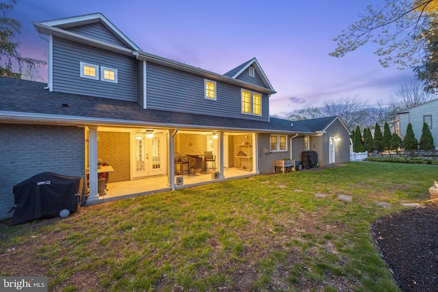 rear view of property featuring a yard, brick siding, and a patio area