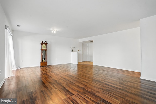 unfurnished living room featuring baseboards, dark wood-style floors, and visible vents