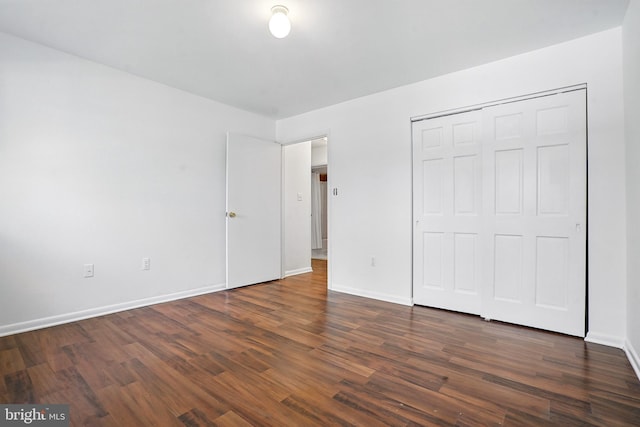 unfurnished bedroom with dark wood-type flooring, baseboards, and a closet
