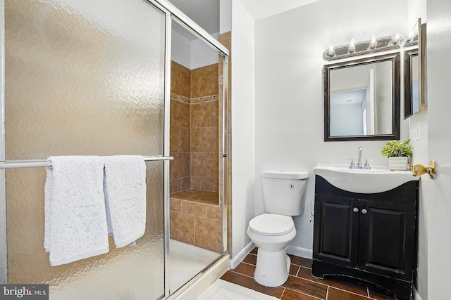 full bathroom featuring toilet, vanity, a stall shower, and baseboards