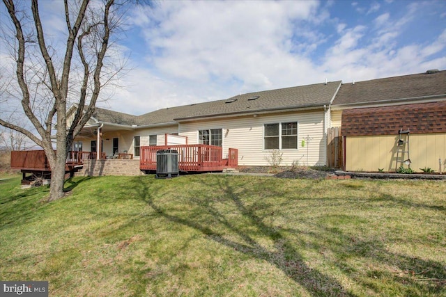 back of property with a shingled roof, a yard, central air condition unit, and a deck