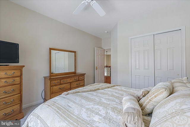 bedroom featuring a ceiling fan, baseboards, a closet, lofted ceiling, and light carpet