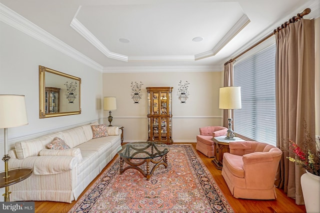 living area featuring crown molding, a tray ceiling, and wood finished floors