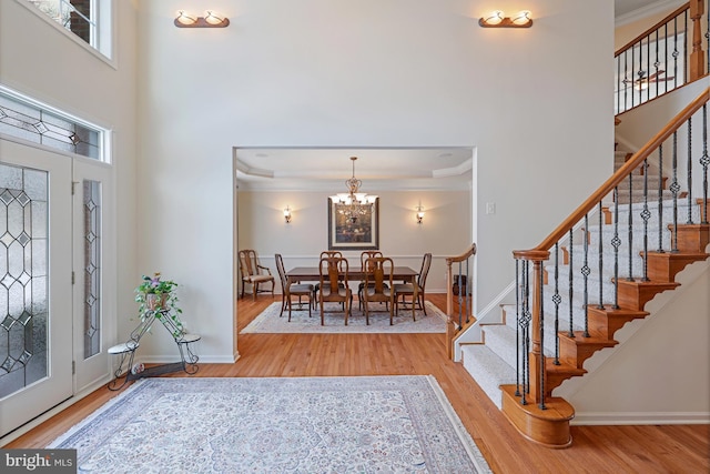 entryway with crown molding, a notable chandelier, and wood finished floors