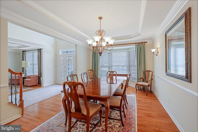 dining area with crown molding, an inviting chandelier, a healthy amount of sunlight, and light wood-type flooring