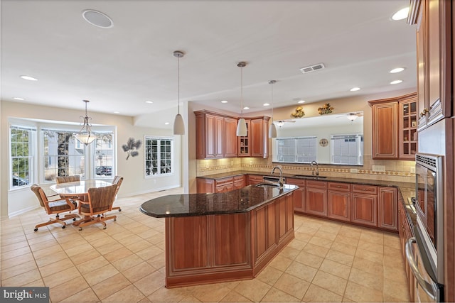 kitchen with a sink, backsplash, brown cabinets, and visible vents