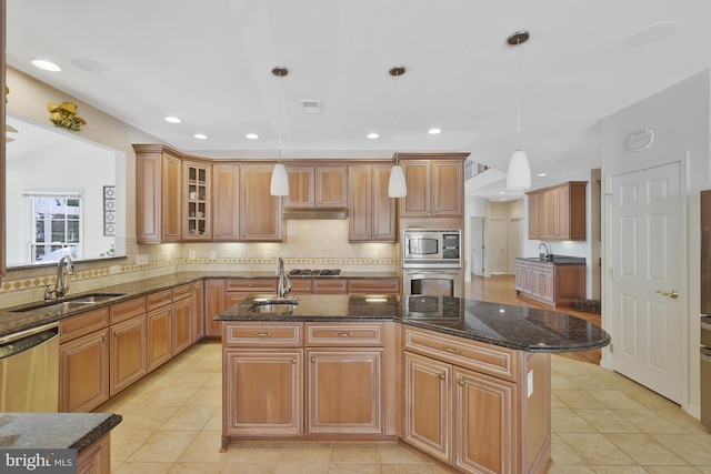 kitchen featuring a sink, appliances with stainless steel finishes, tasteful backsplash, and an island with sink