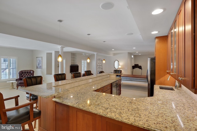 kitchen featuring open floor plan, brown cabinets, and freestanding refrigerator