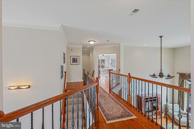 corridor featuring visible vents, wood finished floors, an upstairs landing, an inviting chandelier, and ornamental molding