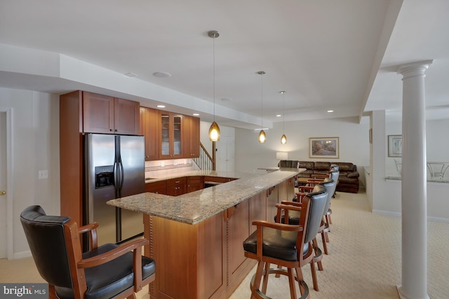 kitchen featuring a breakfast bar, glass insert cabinets, light carpet, light stone countertops, and stainless steel fridge with ice dispenser