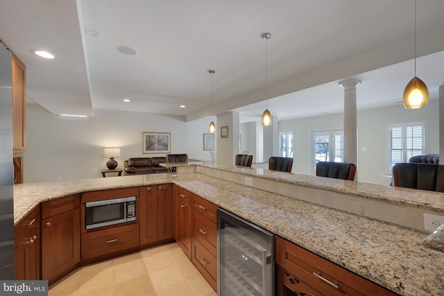 kitchen featuring beverage cooler, open floor plan, stainless steel microwave, and light stone countertops