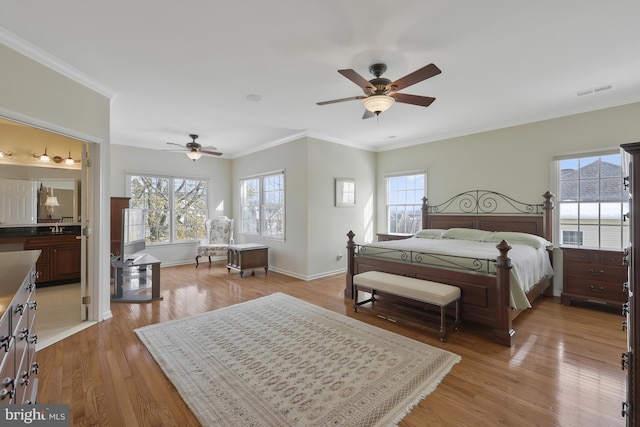 bedroom with crown molding, multiple windows, and light wood-style floors