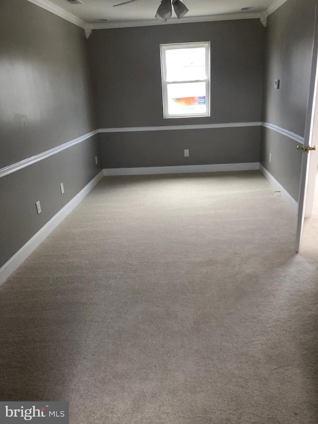 carpeted empty room featuring baseboards, ceiling fan, and crown molding