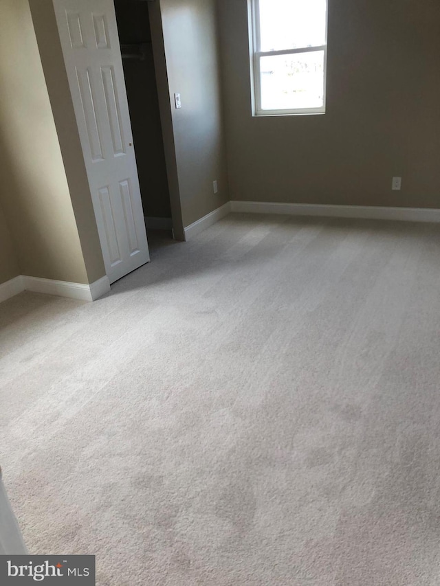 unfurnished bedroom featuring light carpet and baseboards