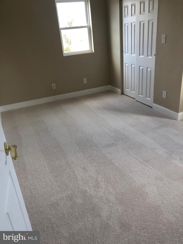 unfurnished bedroom with baseboards, carpet floors, and a closet