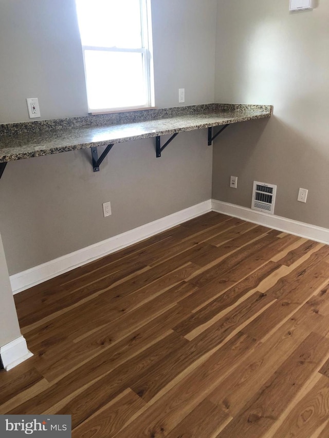 interior space with dark wood-style floors, visible vents, and baseboards
