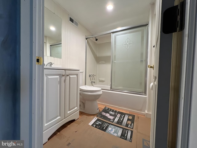 bathroom featuring toilet, vanity, wood finished floors, enclosed tub / shower combo, and visible vents