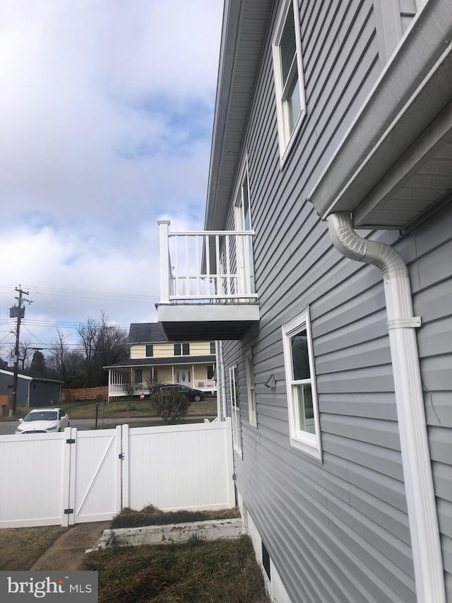 view of property exterior featuring a balcony, a gate, and fence