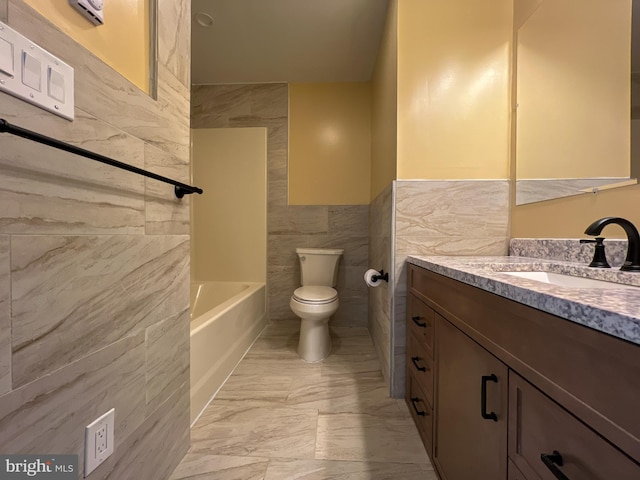 bathroom featuring toilet, vanity, a tub, marble finish floor, and tile walls