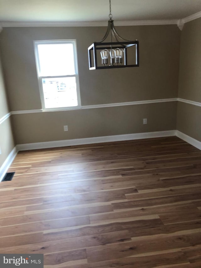 unfurnished dining area with visible vents, a chandelier, baseboards, ornamental molding, and wood finished floors