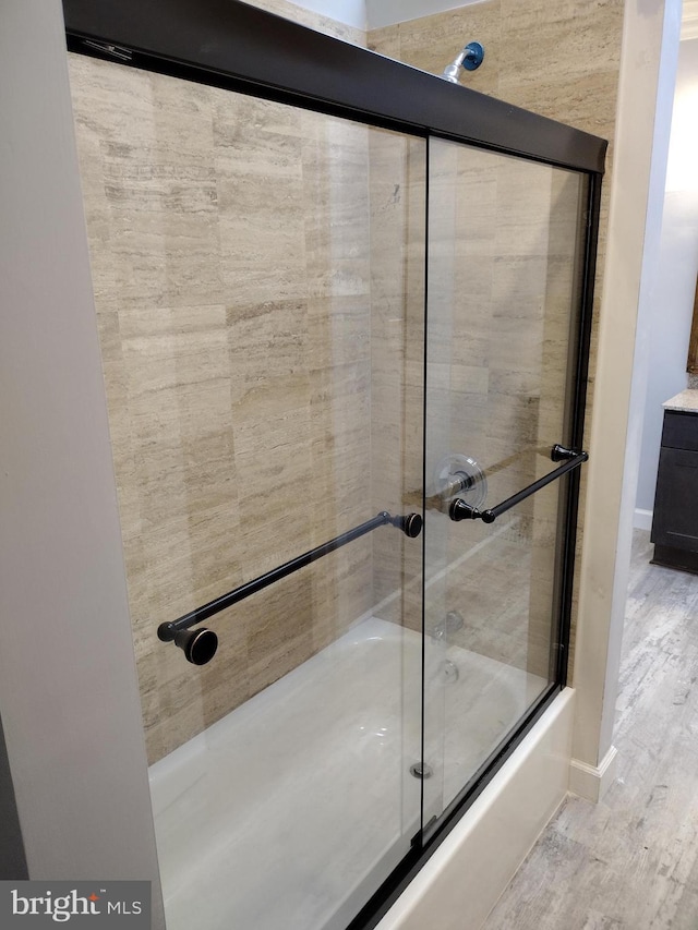 bathroom with combined bath / shower with glass door and wood finished floors