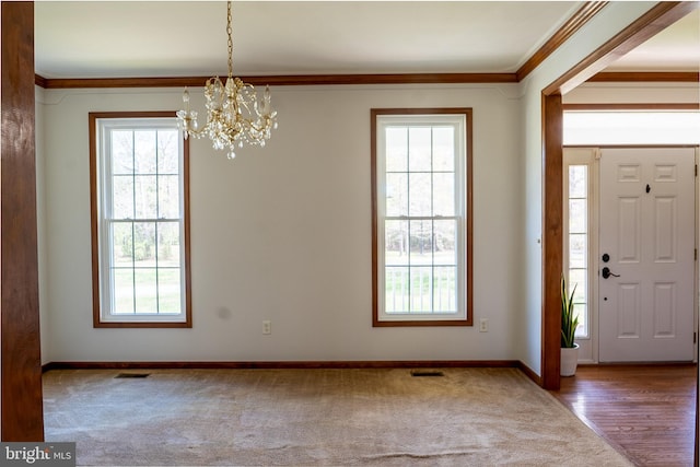 carpeted foyer entrance featuring a wealth of natural light, a notable chandelier, and visible vents