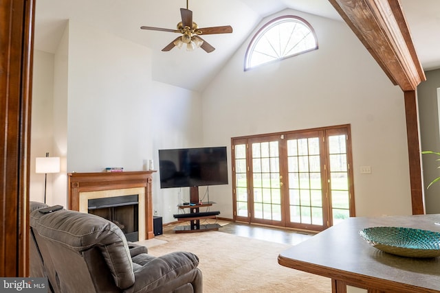 living room featuring high vaulted ceiling, a fireplace with flush hearth, and a ceiling fan