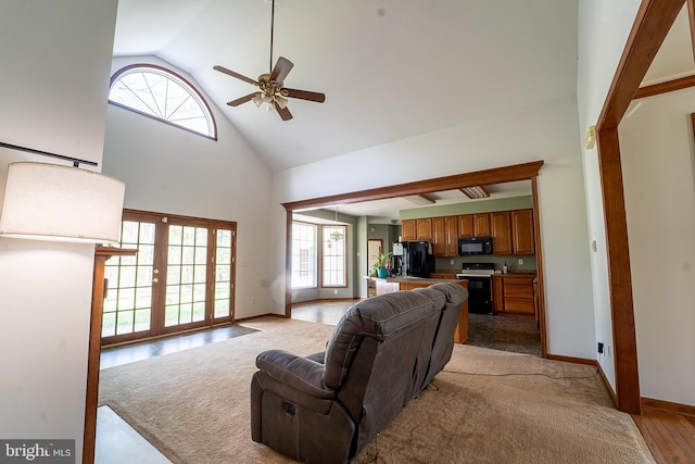 living room with high vaulted ceiling, ceiling fan, baseboards, and light wood-style flooring