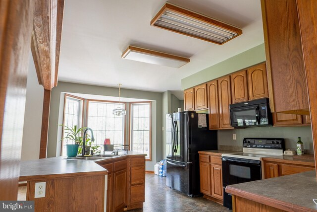 kitchen with brown cabinets, hanging light fixtures, a sink, and black appliances