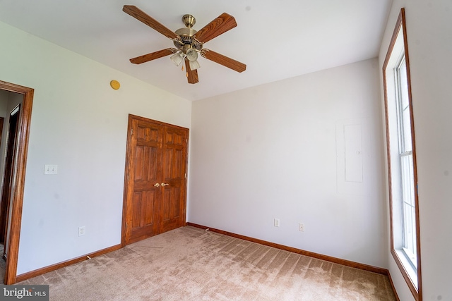 empty room with plenty of natural light, a ceiling fan, baseboards, and light colored carpet