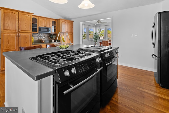 kitchen with freestanding refrigerator, wood finished floors, black gas range, and a ceiling fan