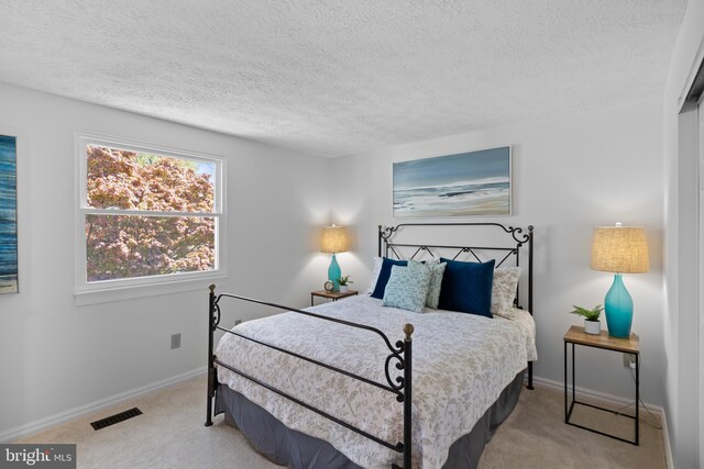 bedroom with baseboards, visible vents, carpet floors, and a textured ceiling