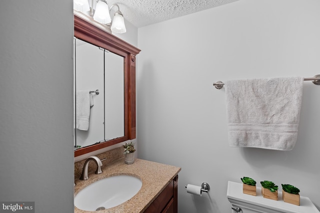 half bath featuring toilet, vanity, and a textured ceiling