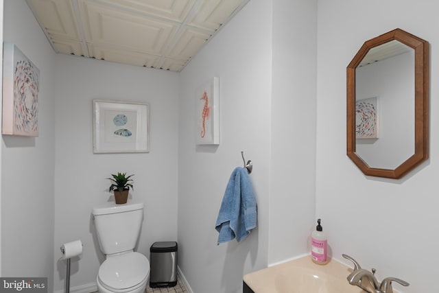 half bathroom featuring toilet, a sink, and baseboards