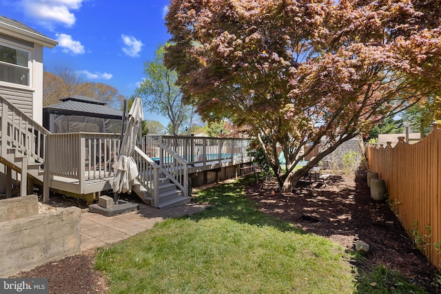 view of yard with a fenced backyard, a wooden deck, a gazebo, and stairway