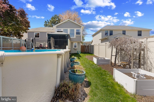 rear view of property with a gazebo, a fenced backyard, a yard, a fenced in pool, and a garden