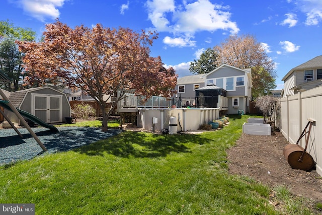 view of yard featuring fence, a wooden deck, a storage unit, and an outdoor structure