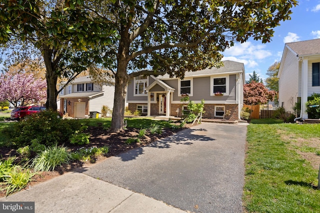 raised ranch with fence, a front lawn, and brick siding