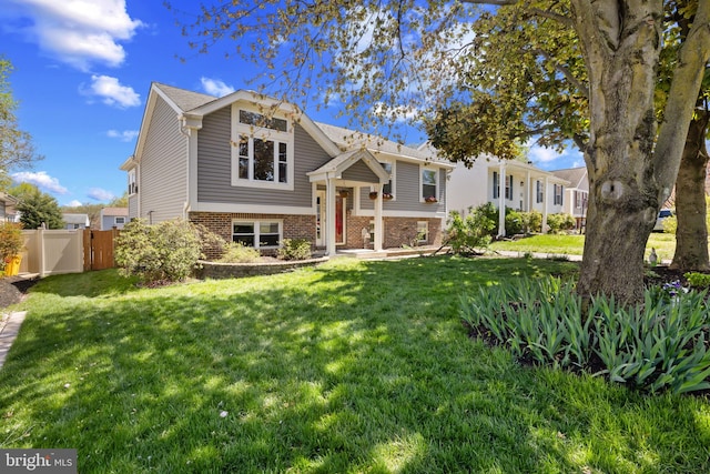 split foyer home with brick siding, a front lawn, and fence