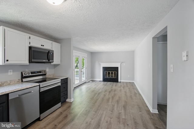 5694 Singletree Dr, Frederick, MD 21703 - kitchen featuring stainless steel appliances, light wood-style floors, light countertops, white cabinetry, and a textured ceiling