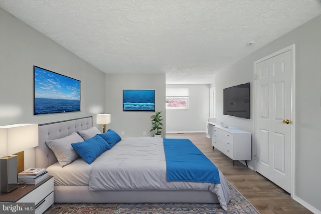 5694 Singletree Dr, Frederick, MD 21703 - bedroom featuring a textured ceiling, wood finished floors, and baseboards